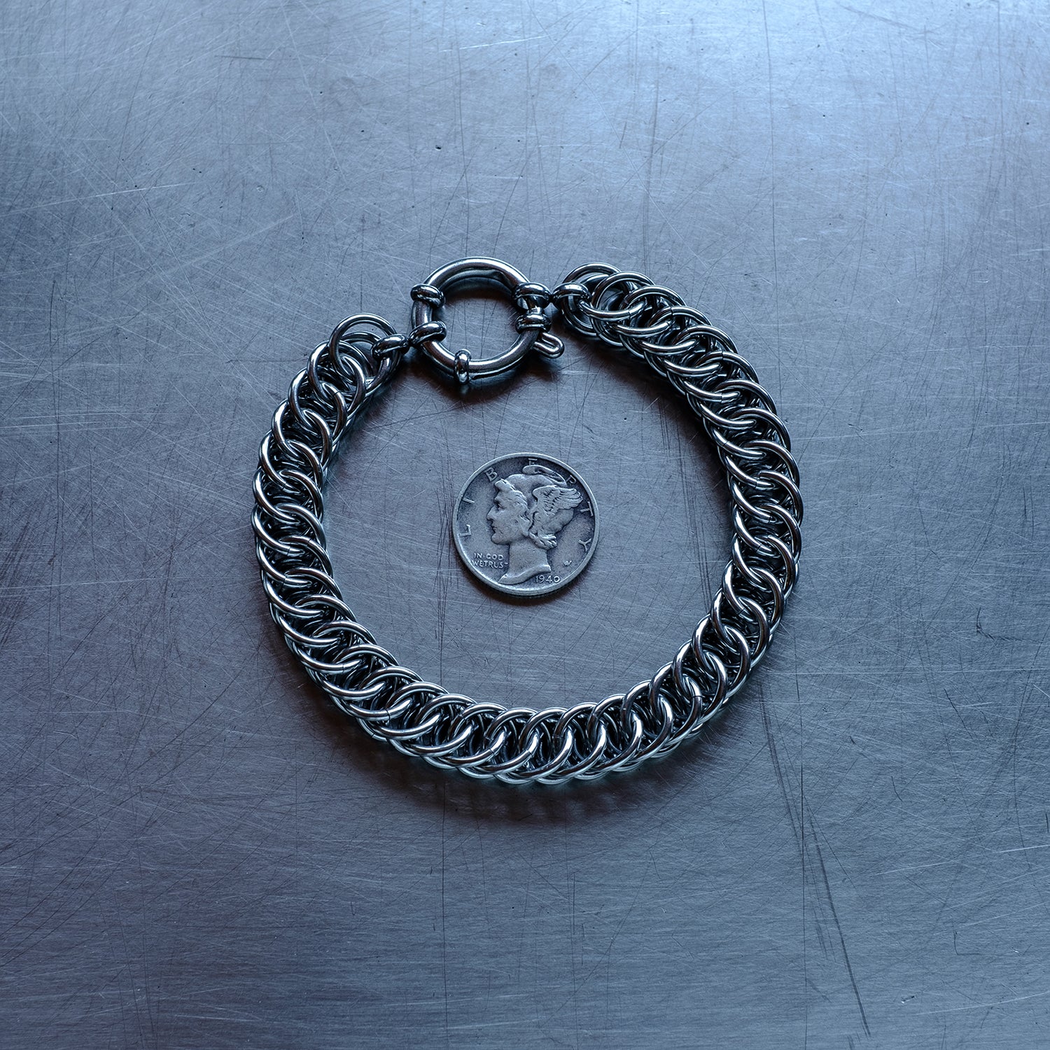 Bold Half Persian weave chain bracelet made with 304 stainless steel on a stainless steel surface with a liberty dime for scale