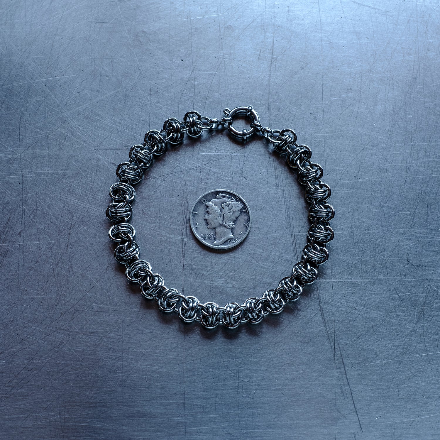 Classic in size, Barrel weave chain bracelet made with 304 stainless steel on a stainless steel surface with a liberty dime for scale