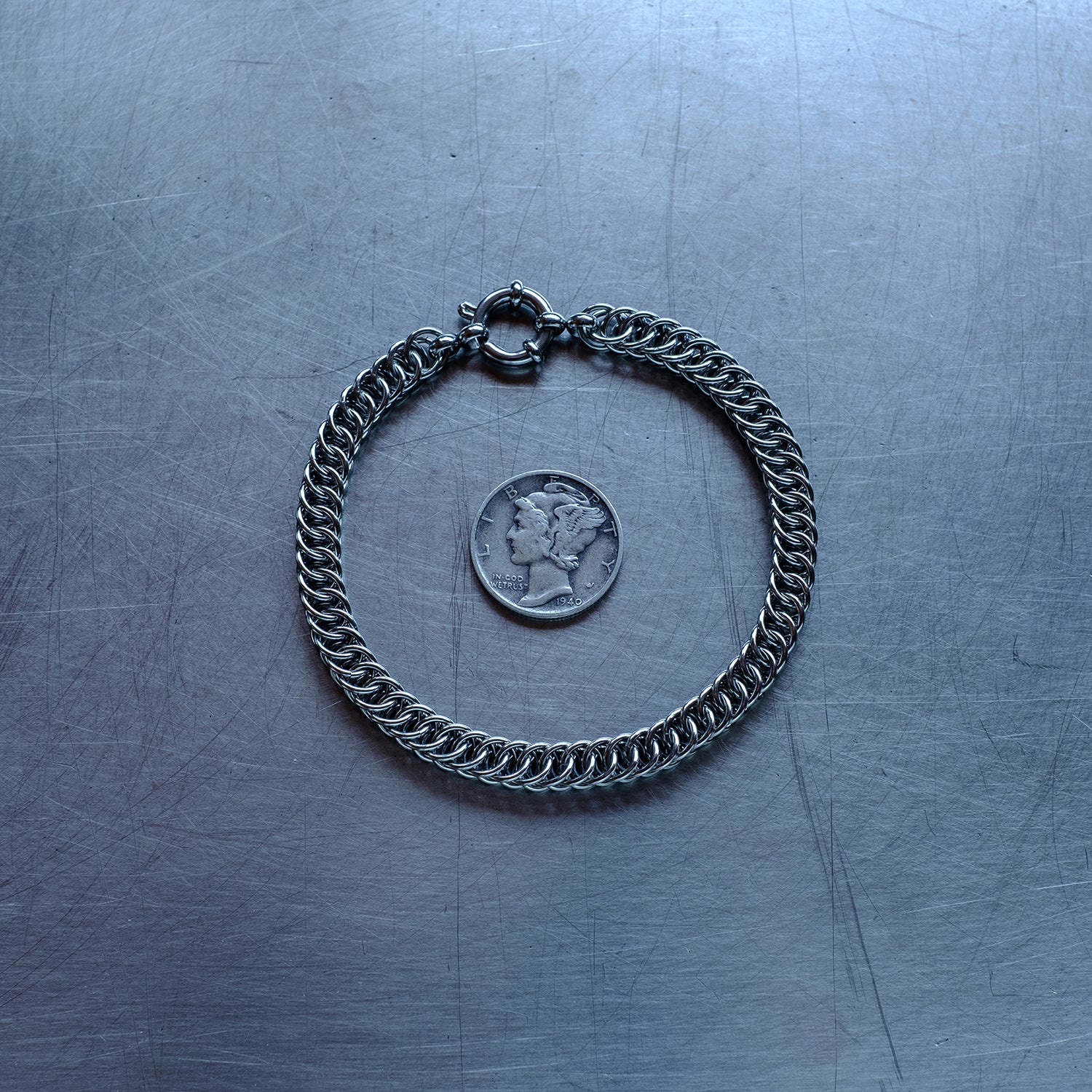 Dainty, Half persian weave chain bracelet made with 304 stainless steel on a stainless steel surface with a liberty dime for scale