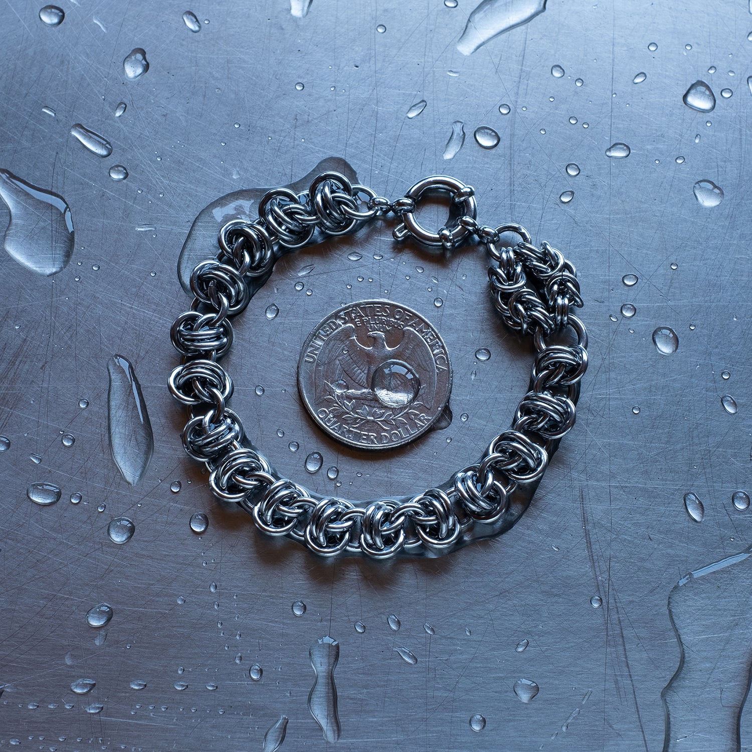 Bold Barrel weave with Byzantine Head Snake chain bracelet made with 304 stainless steel on a wet stainless steel surface with a quarter for scale