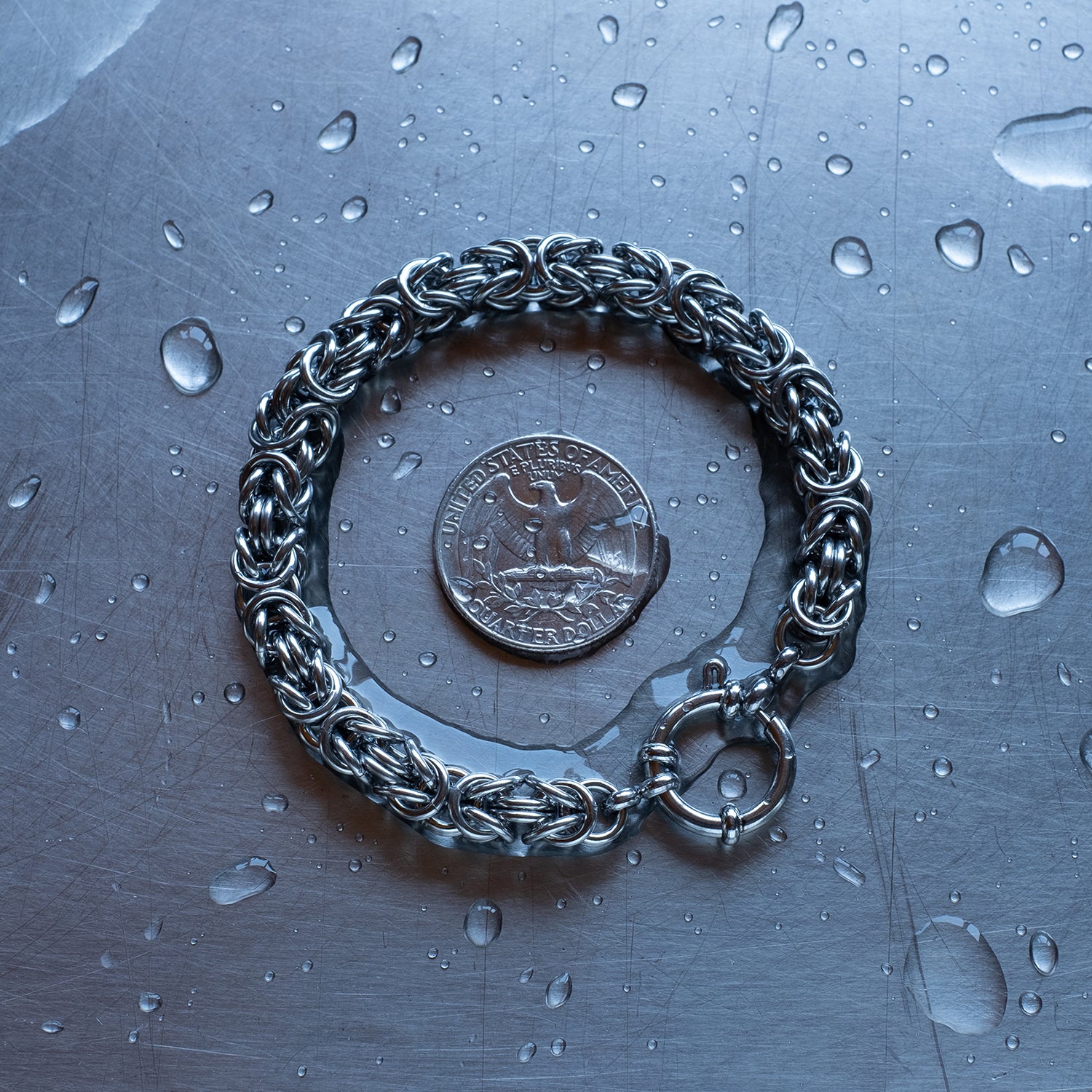 Bold byzantine weave 304 stainless steel chain bracelet on a stainless steel surface with a quarter for scale