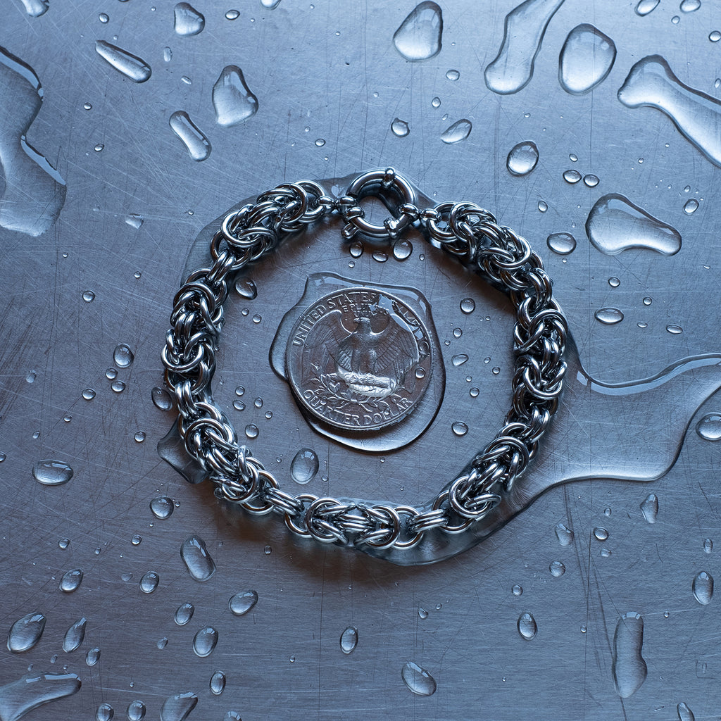 Bold Byzantine weave chain bracelet in units configuration made with 304 stainless steel on a wet stainless steel surface with a quarter for scale