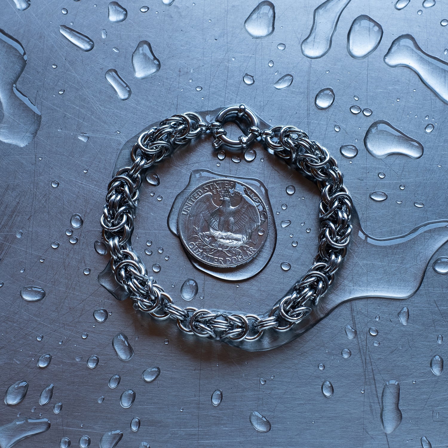 Bold Byzantine weave chain bracelet in units configuration made with 304 stainless steel on a wet stainless steel surface with a quarter for scale