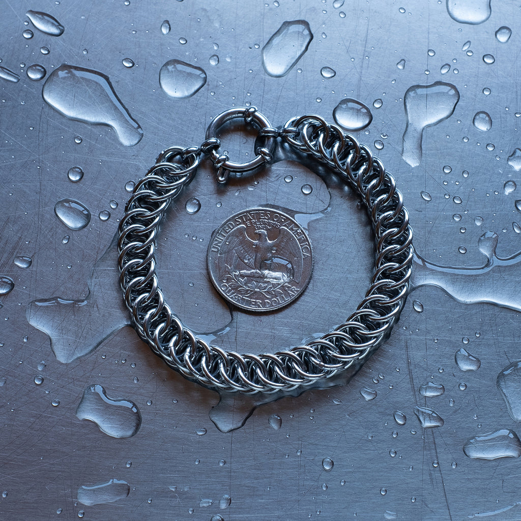 Bold Half Persian weave chain bracelet made with 304 stainless steel on a wet stainless steel surface with a quarter for scale