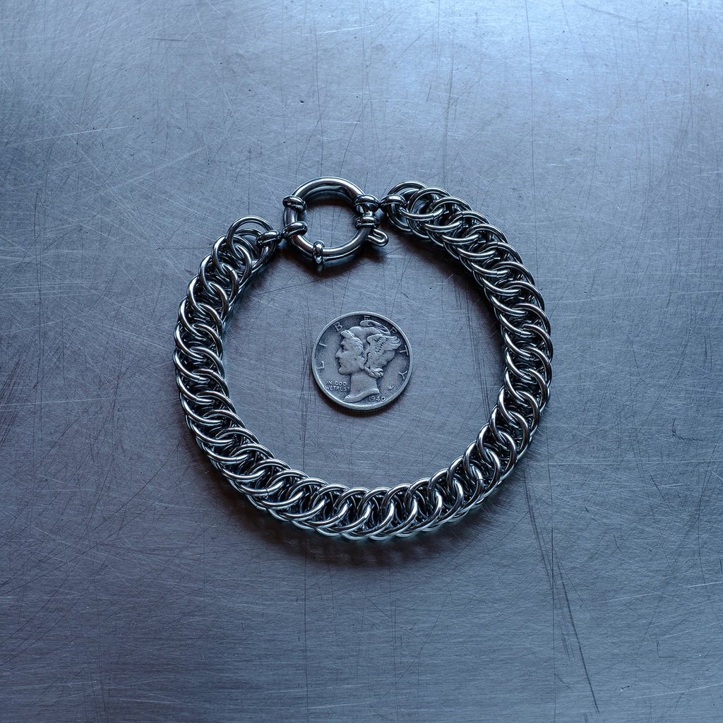 Bold Half Persian weave chain bracelet made with 304 stainless steel on a stainless steel surface with a liberty dime for scale
