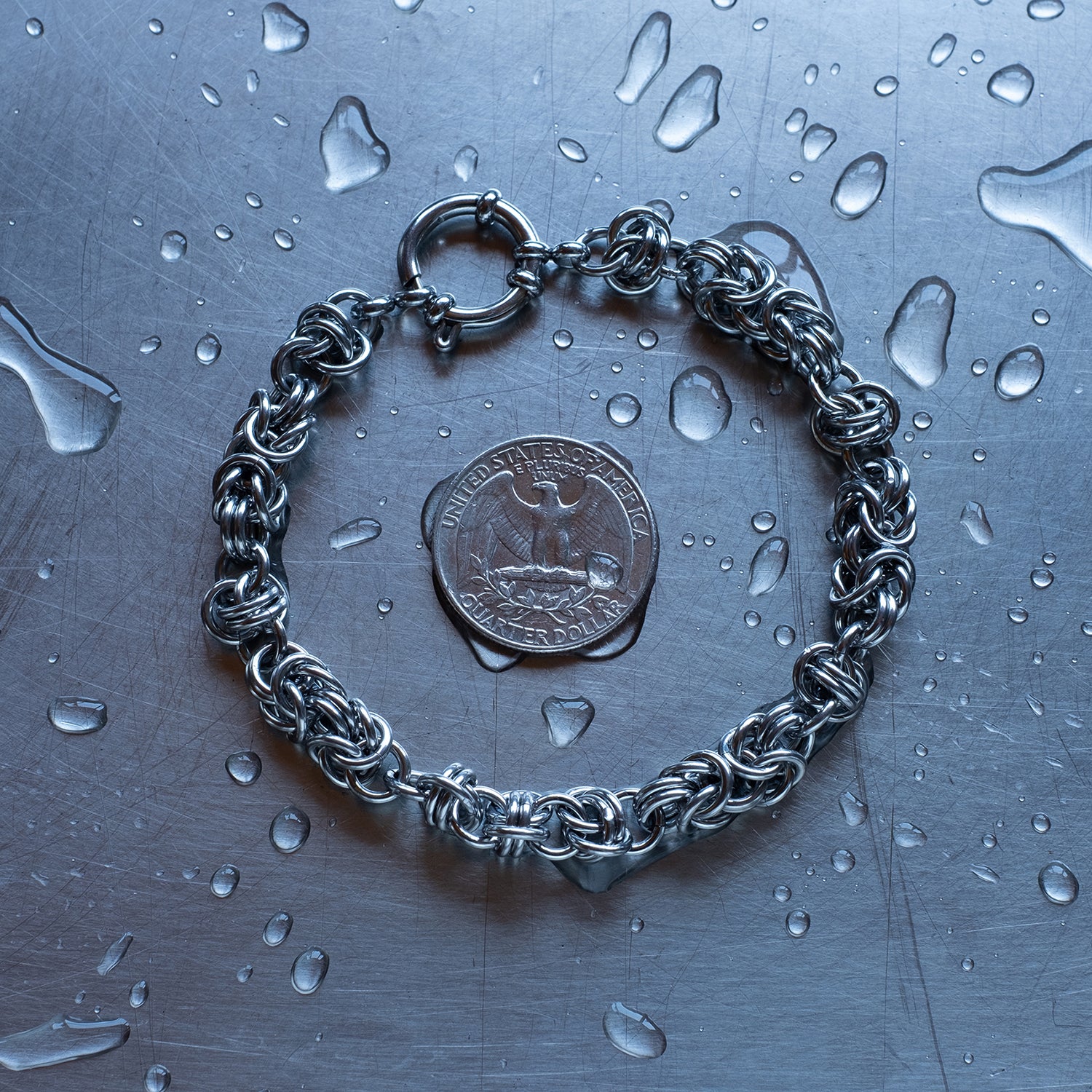 Bold Byzantine and Barrel weave chain bracelet in alternating units configuration made with 304 stainless steel on a wet stainless steel surface with a quarter for scale