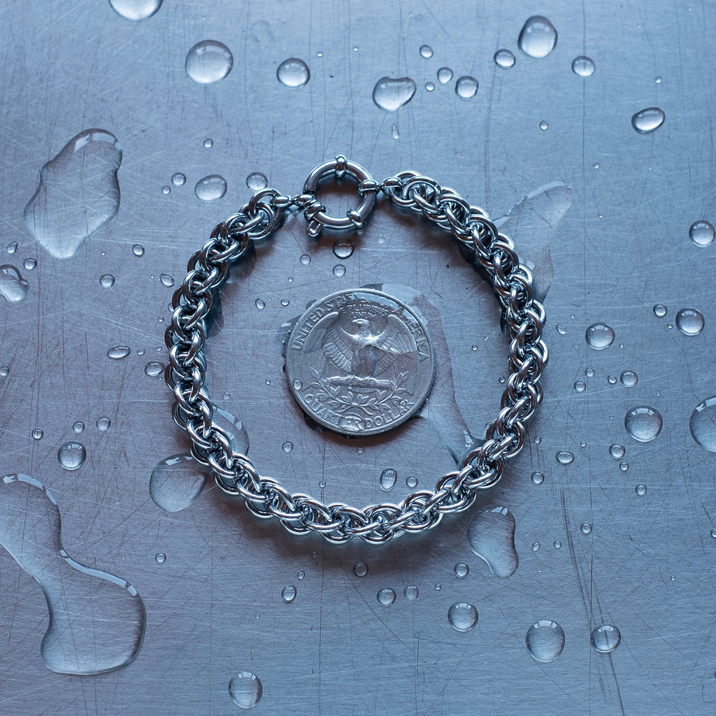 classic jpl3 weave chain bracelet made with 304 stainless steel on a wet stainless steel surface with a quarter for scale