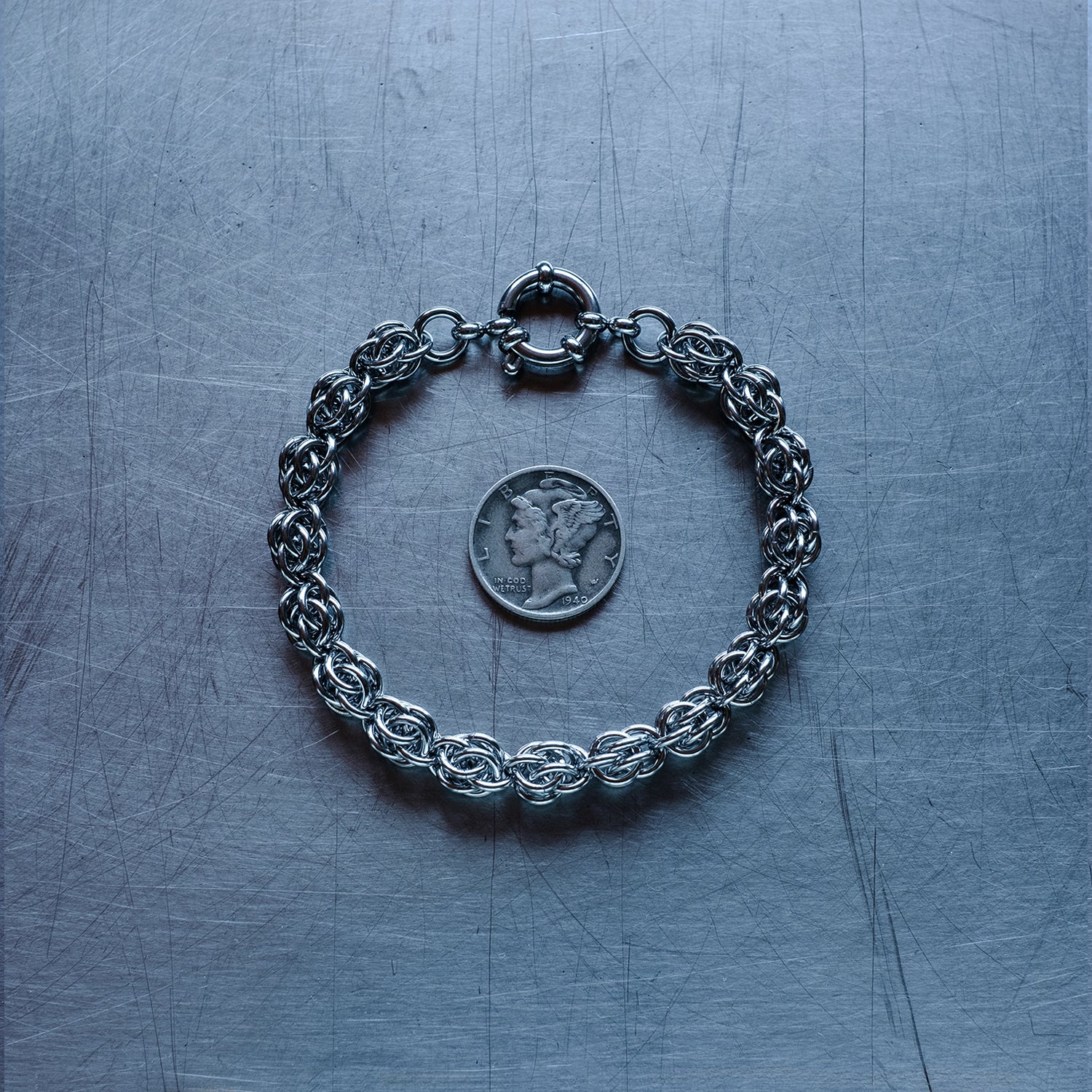 Classic Sweet Pea weave chain bracelet made with 304 stainless steel on a stainless steel surface with a liberty dime for scale