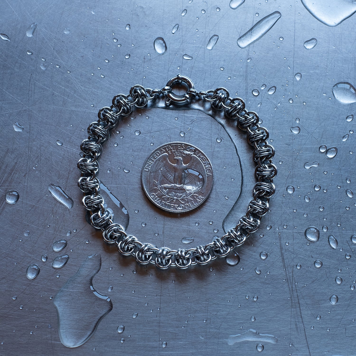 Classic in size, Barrel weave chain bracelet made with 304 stainless steel on a wet stainless steel surface with a quarter for scale
