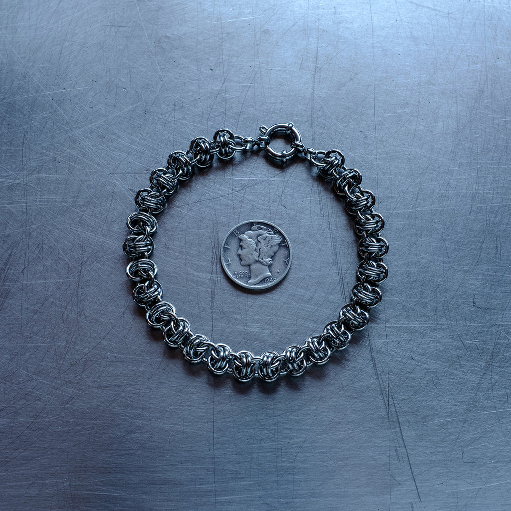 Classic in size, Barrel weave chain bracelet made with 304 stainless steel on a stainless steel surface with a liberty dime for scale