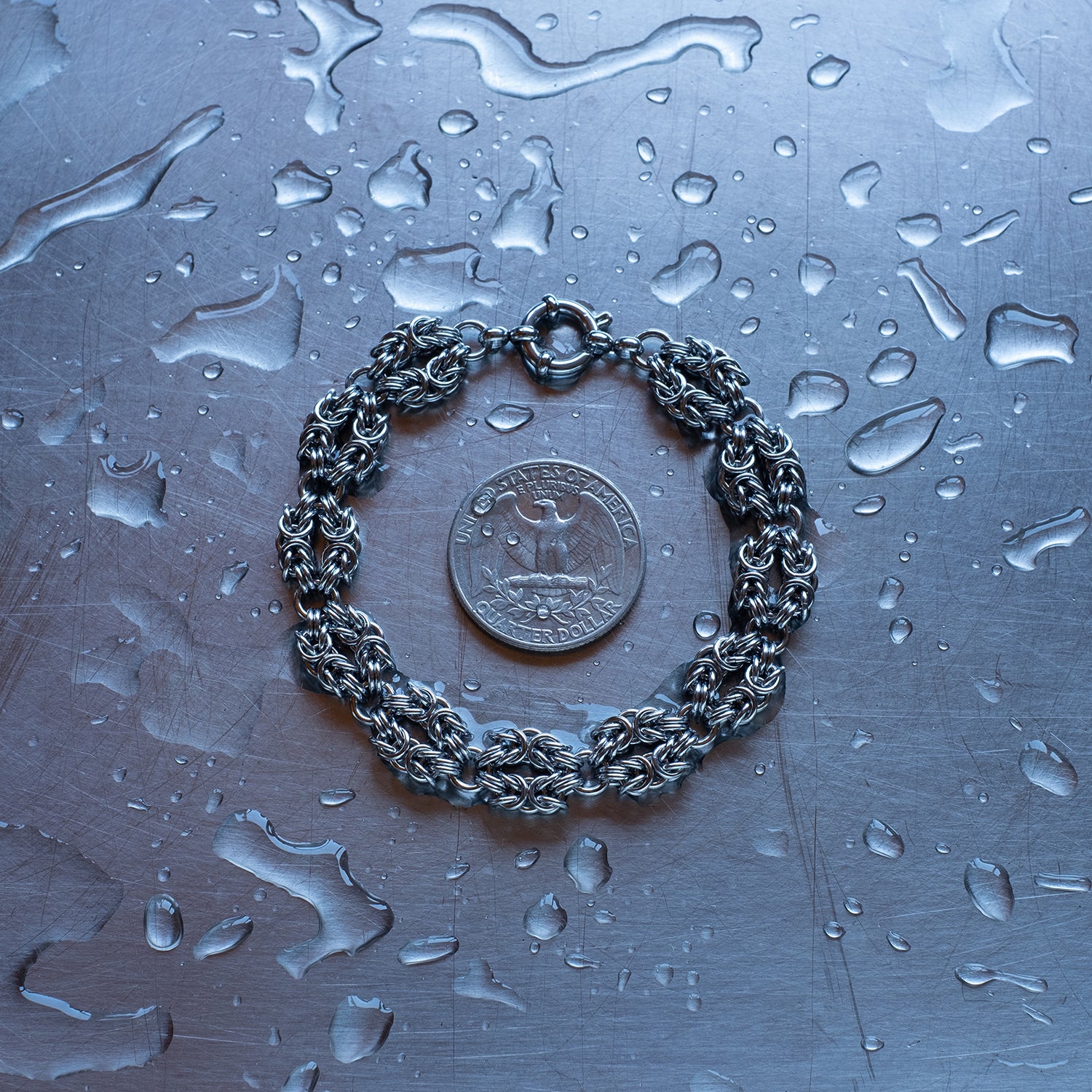Classic in size byzantine weave in "heads" configuration made with 304 stainless steel chain bracelet on a stainless steel surface with a quarter for scale