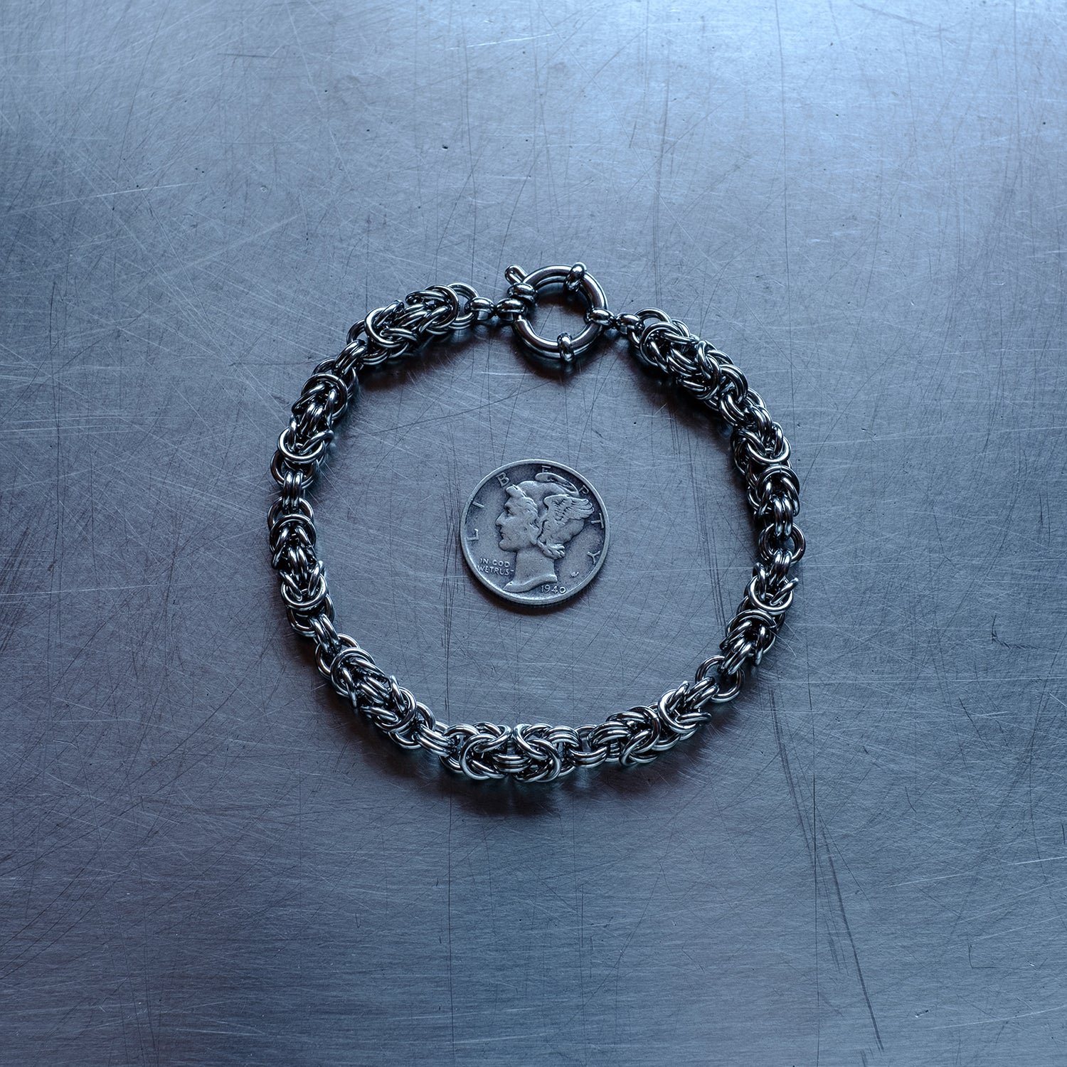 Classic sized Byzantine weave chain bracelet in units configuration made with 304 stainless steel on a stainless steel surface with a liberty dime for scale