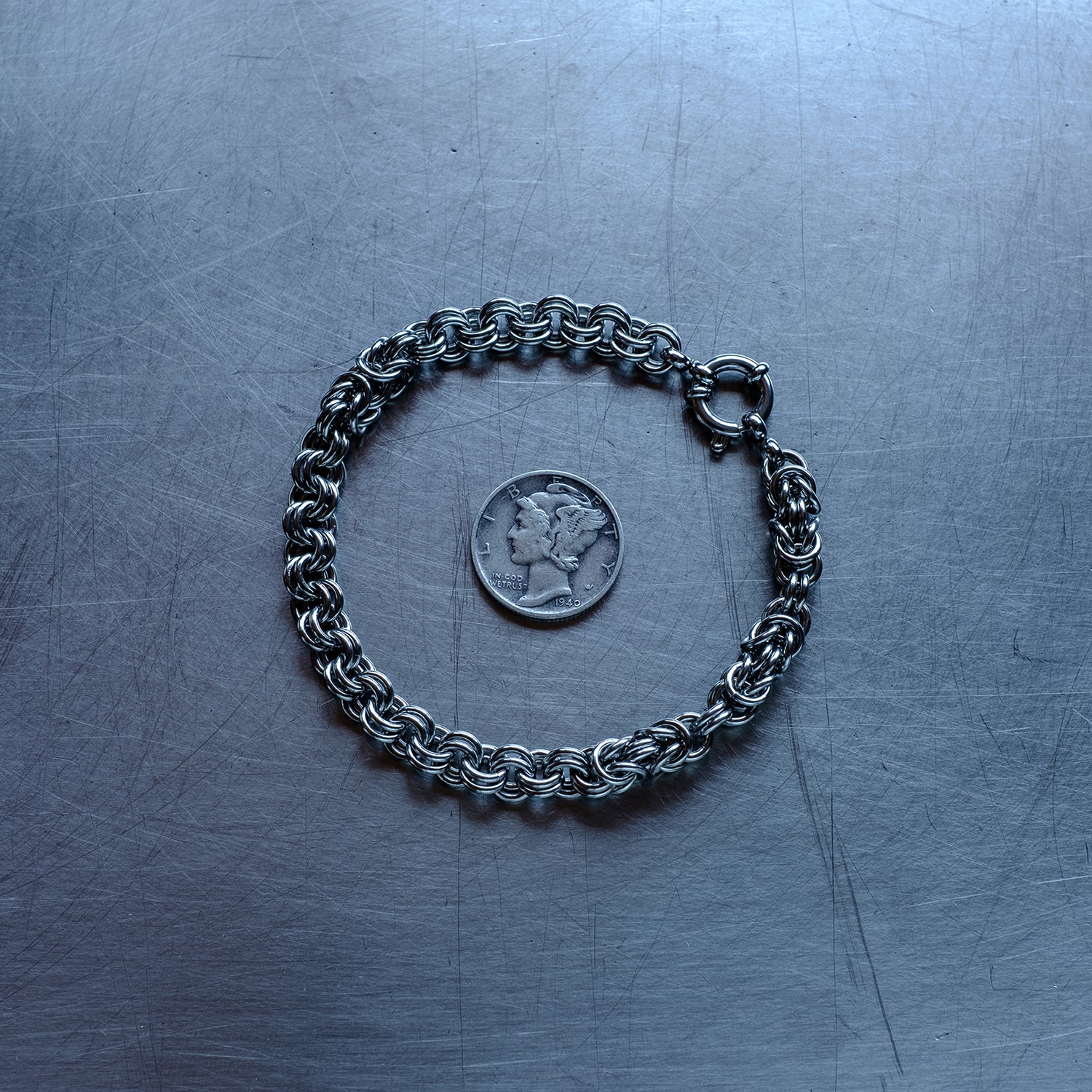 Classic in weave size, sections of Byzantine weave with 2 in 1 weave, chain bracelet with medieval vibes made with 304 stainless steel on a stainless steel surface with a liberty dime for scale
