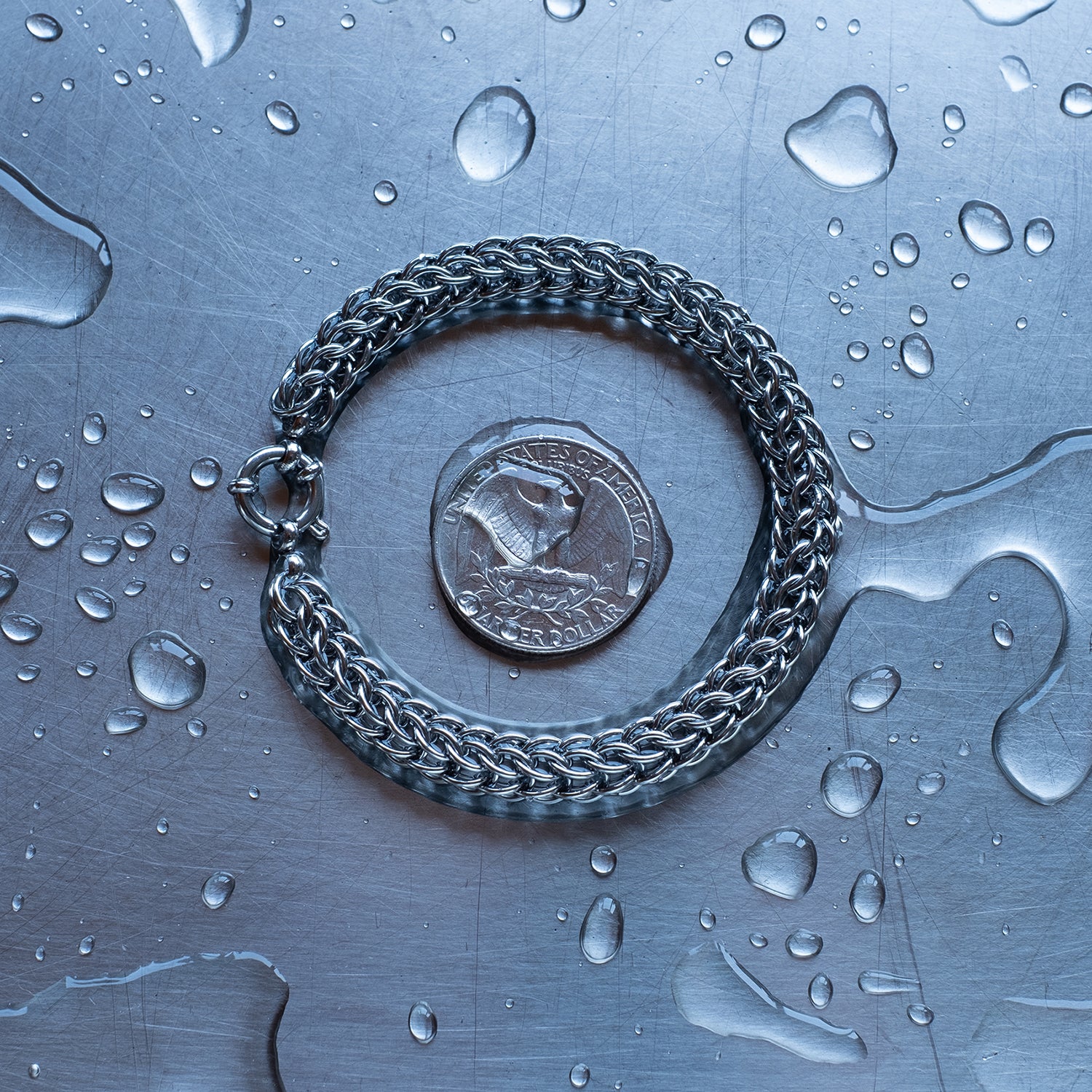 Classic in size, Full Persian weave chain bracelet made with 304 stainless steel on a wet stainless steel surface with a quarter for scale
