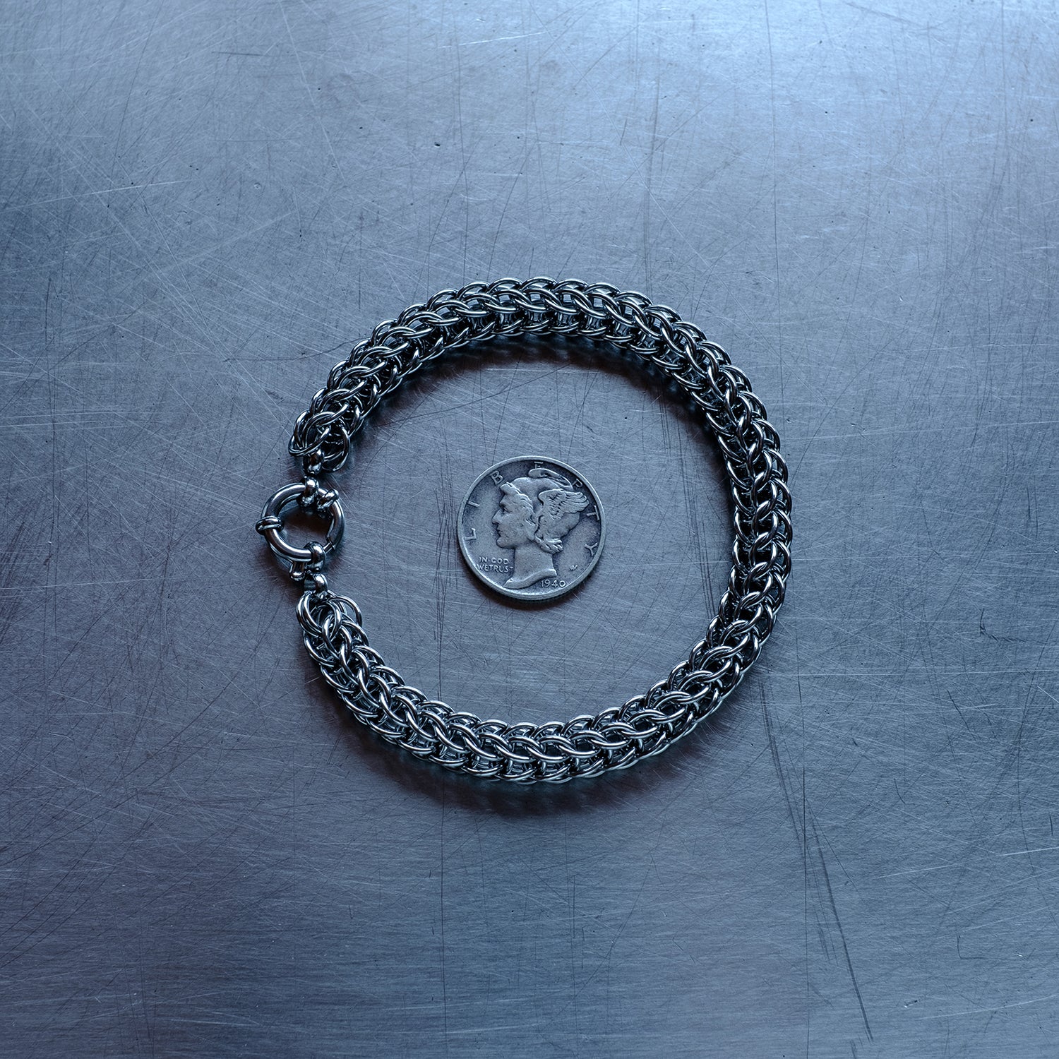 Classic in size, Full Persian weave chain bracelet made with 304 stainless steel on a stainless steel surface with a liberty dime for scale