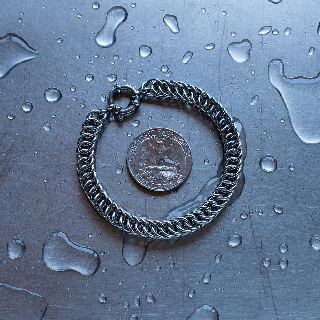 Classic in size, Half persian weave chain bracelet made with 304 stainless steel on a wet stainless steel surface with a quarter for scale