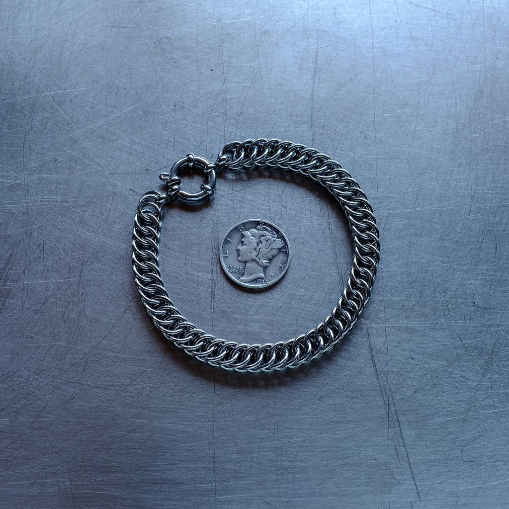 Classic in size, Half persian weave chain bracelet made with 304 stainless steel on a stainless steel surface with a liberty dime for scale