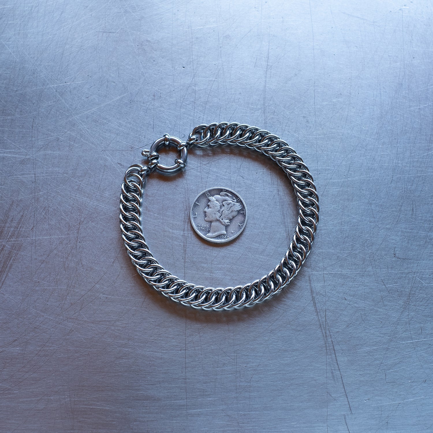 Classic in size, Half persian weave chain bracelet made with 304 stainless steel on a stainless steel surface with a liberty dime for scale