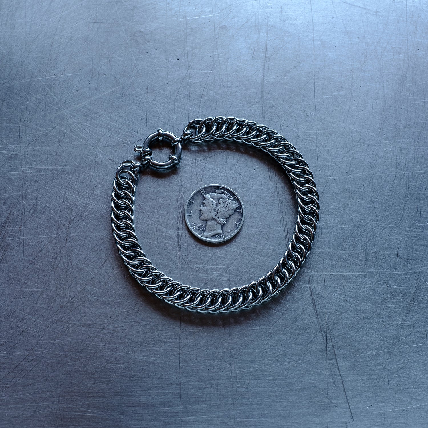 Classic in size, Half persian weave chain bracelet made with 304 stainless steel on a stainless steel surface with a liberty dime for scale