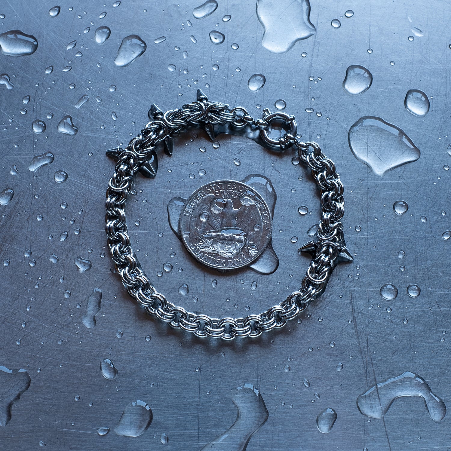 Classic in weave size, sections of Byzantine weave with spikes and 2 in 1 weave, chain bracelet with medieval vibes made with 304 stainless steel on a wet stainless steel surface with a quarter for scale