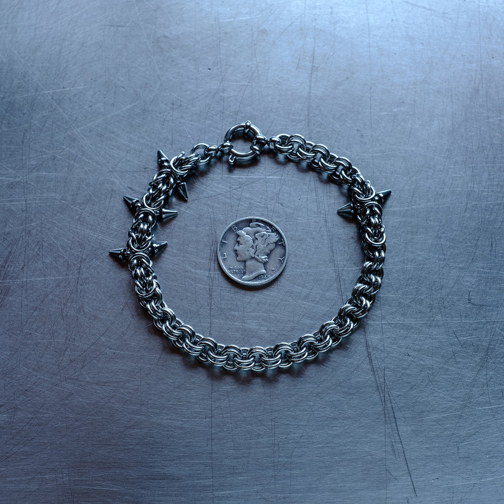 Classic in weave size, sections of Byzantine weave with spikes and 2 in 1 weave, chain bracelet with medieval vibes made with 304 stainless steel on a stainless steel surface with a liberty dime for scale