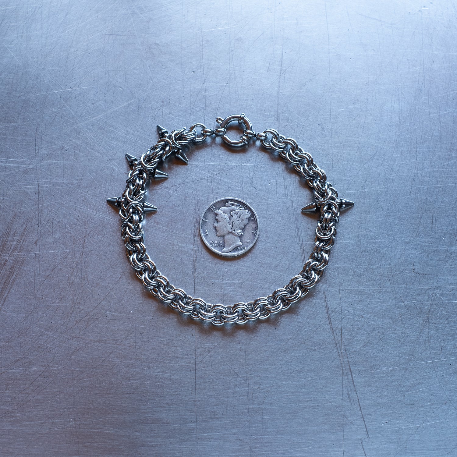 Classic in weave size, sections of Byzantine weave with spikes and 2 in 1 weave, chain bracelet with medieval vibes made with 304 stainless steel on a stainless steel surface with a liberty dime for scale