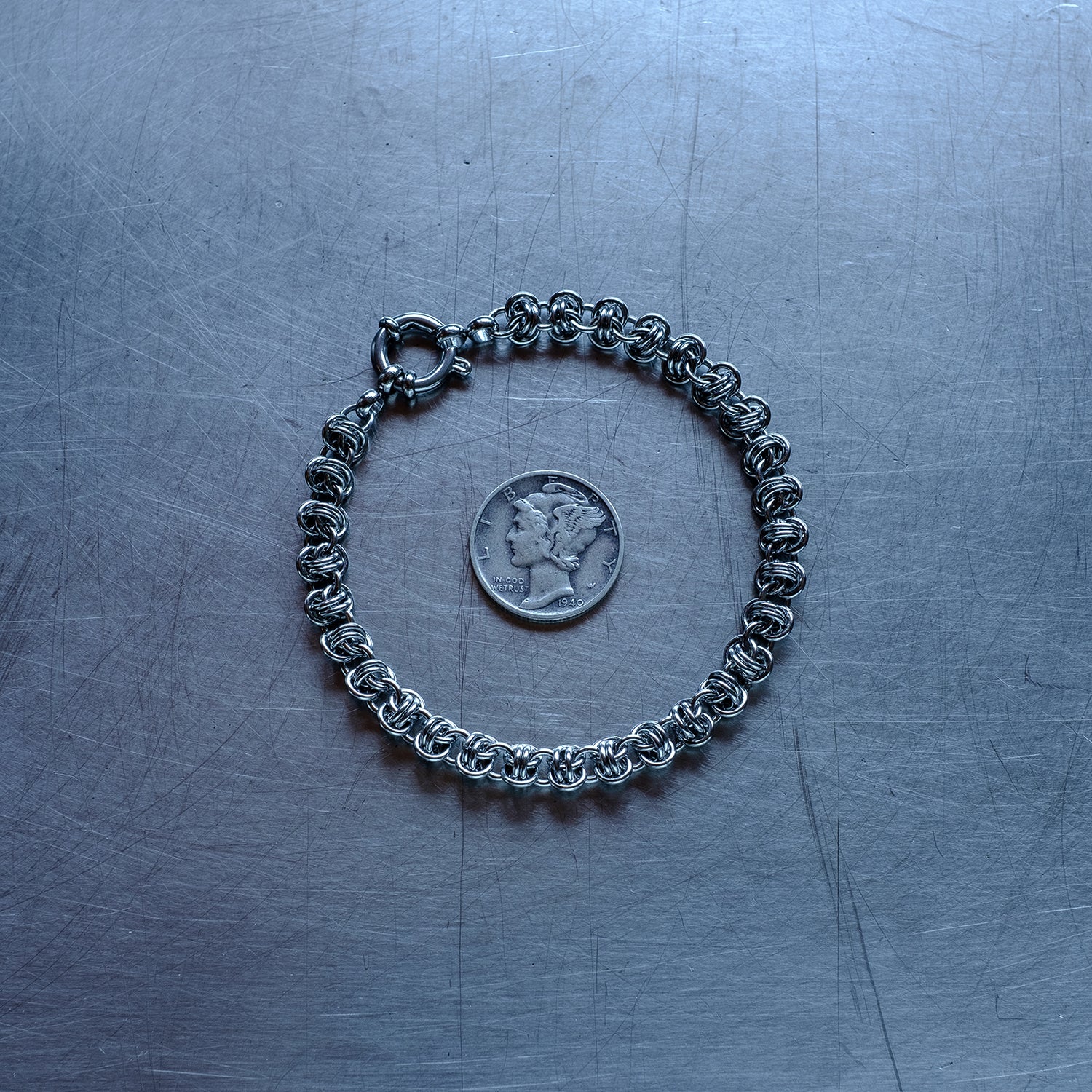 Dainty Barrel weave chain Bracelet made of 304 stainless steel on stainless steel surface with a liberty dime for scale