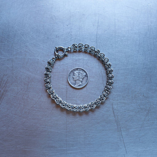 Dainty Barrel weave chain Bracelet made of 304 stainless steel on stainless steel surface with a liberty dime for scale