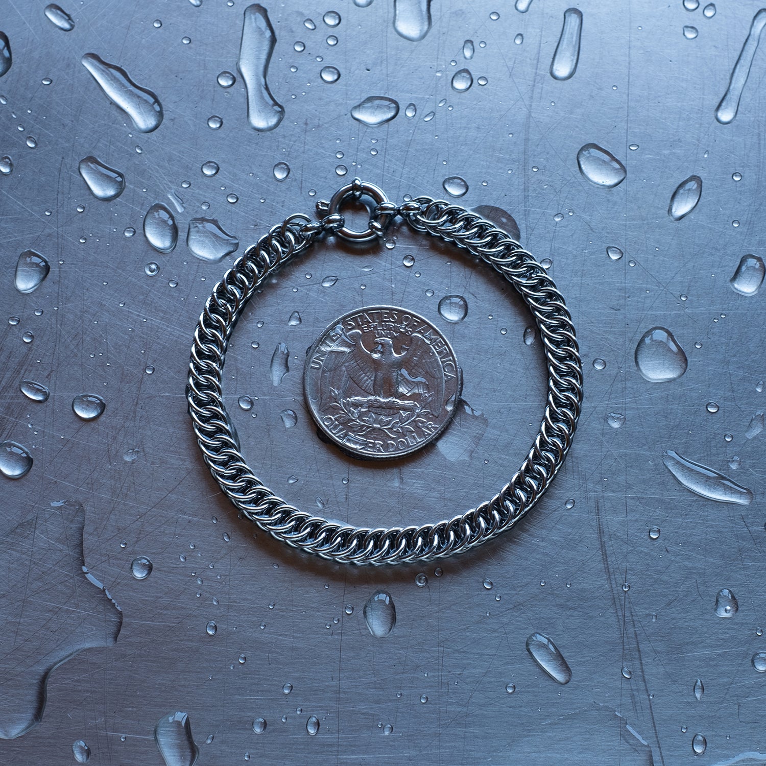 Dainty, Half persian weave chain bracelet made with 304 stainless steel on a wet stainless steel surface with a quarter for scale