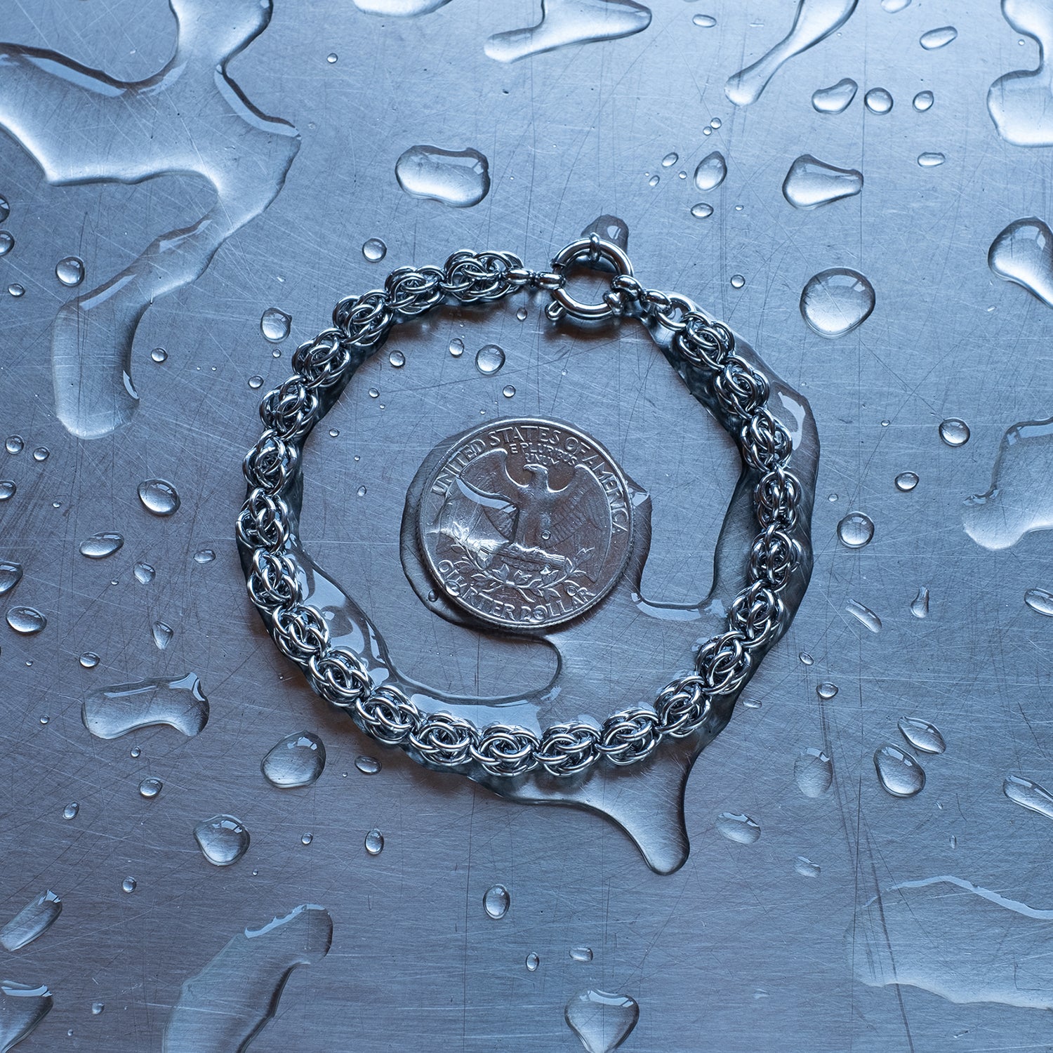 Dainty Sweet Pea weave chain bracelet made with 304 stainless steel on a wet stainless steel surface with a quarter for scale